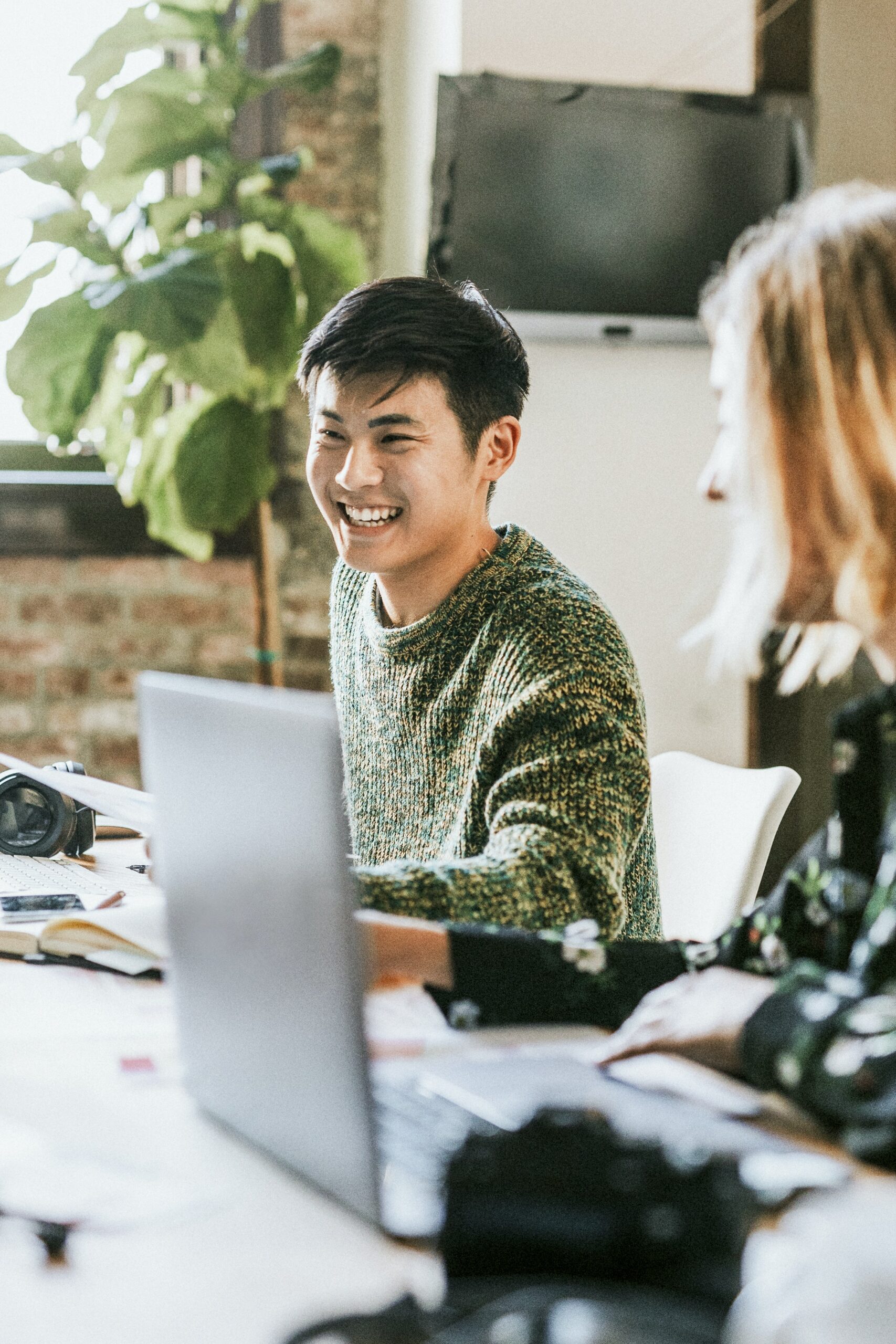 Two people laughing as they collaborate at a table