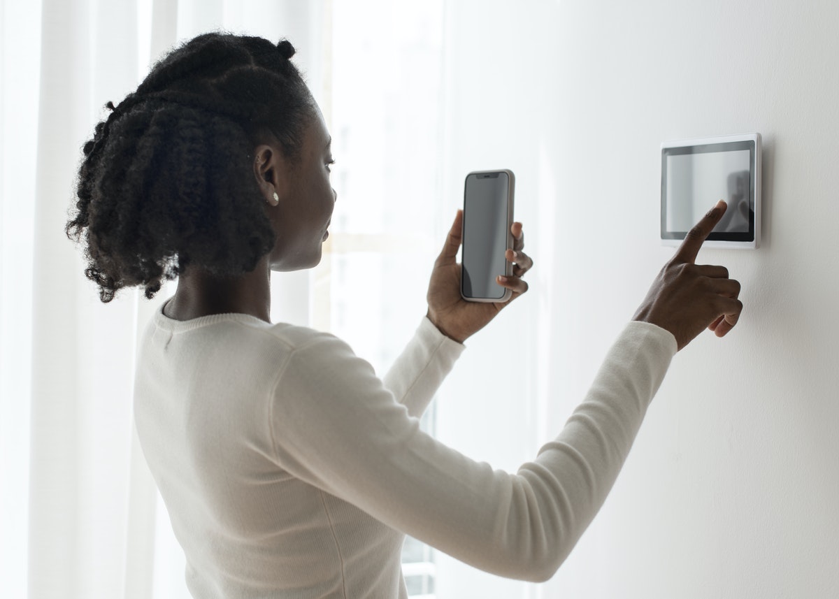 Person adjusting thermastat with their smartphone