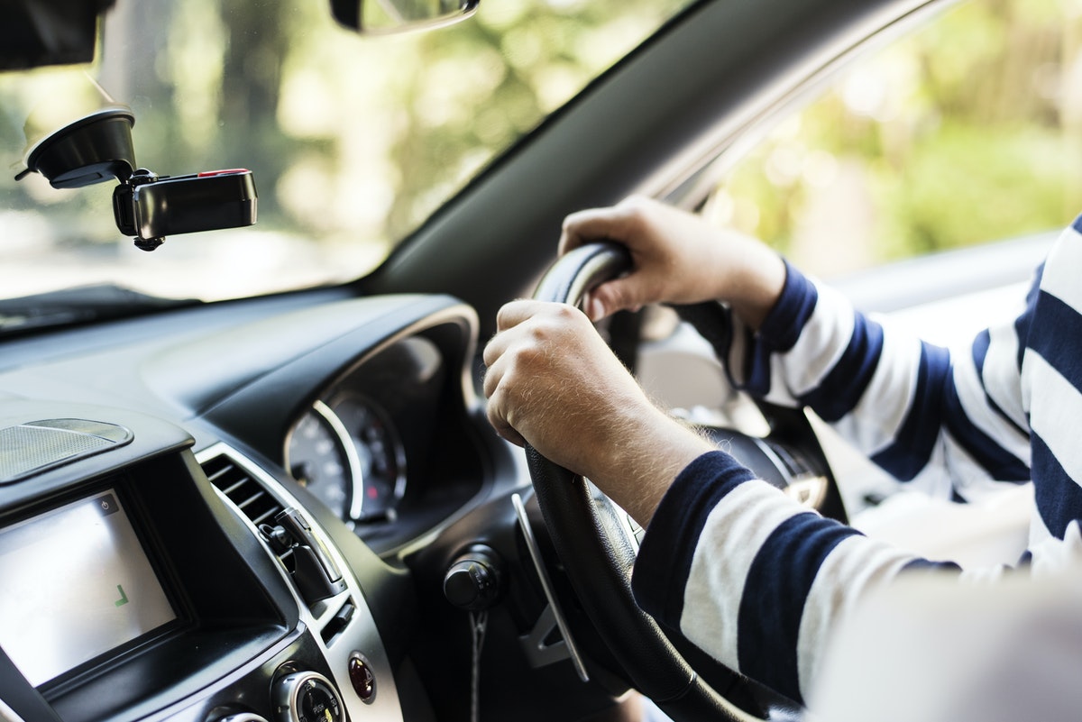 Close up of someone with their hands on a steering wheel