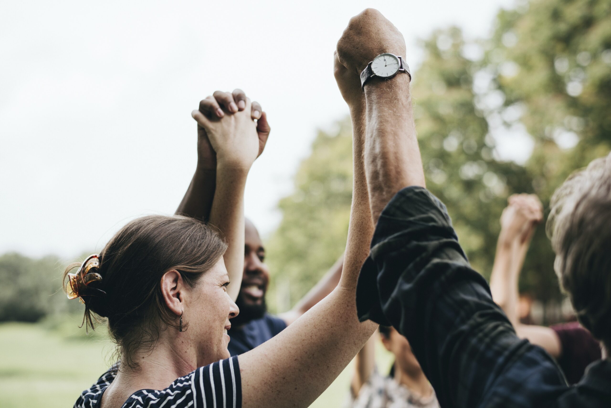 Group of people with intertwined hands in the air